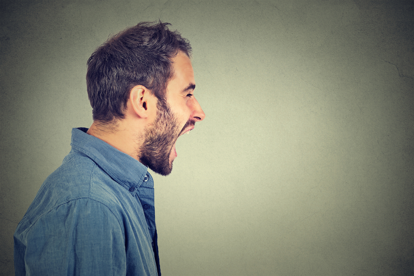 Side profile portrait of young angry man screaming